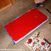 Painting the cornhole table red.