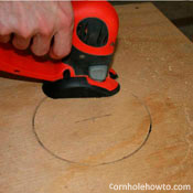 Cutting out the cornhole table's hole with a jigsaw.